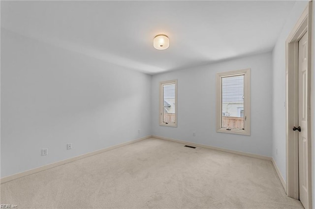 unfurnished room with visible vents, baseboards, and light colored carpet