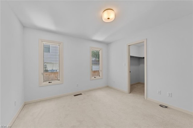 unfurnished bedroom featuring a spacious closet, visible vents, baseboards, and carpet