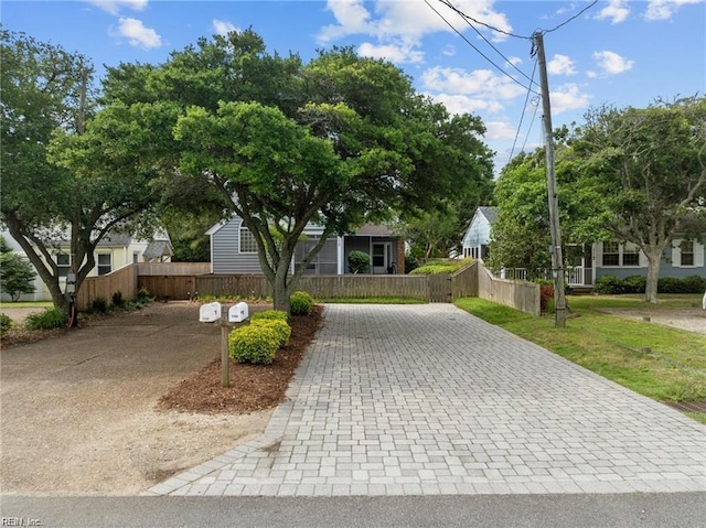 obstructed view of property with a fenced front yard and decorative driveway