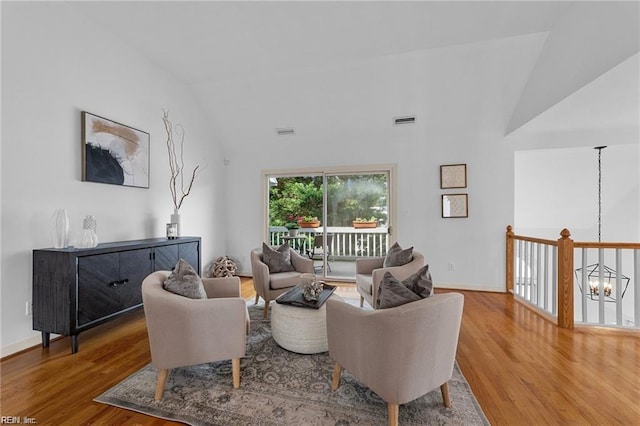 living room with visible vents, baseboards, a chandelier, lofted ceiling, and wood finished floors