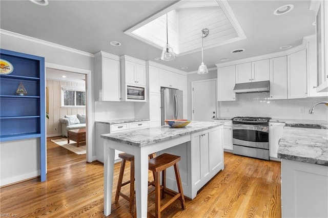 kitchen featuring under cabinet range hood, appliances with stainless steel finishes, a sink, and white cabinetry