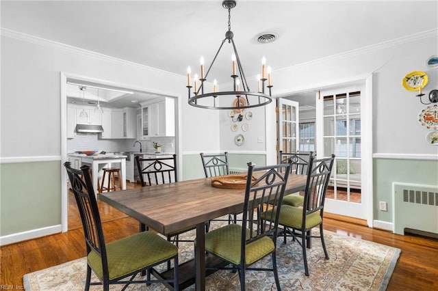 dining area featuring crown molding, radiator heating unit, and wood finished floors