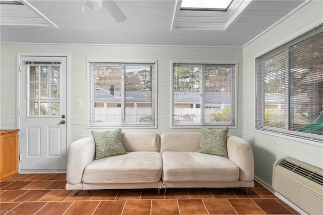 sunroom with a skylight, a wall mounted air conditioner, and a ceiling fan