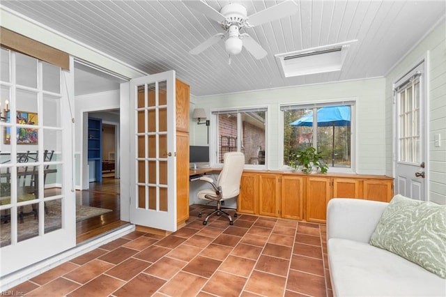 unfurnished office featuring tile patterned flooring, built in desk, crown molding, and a ceiling fan