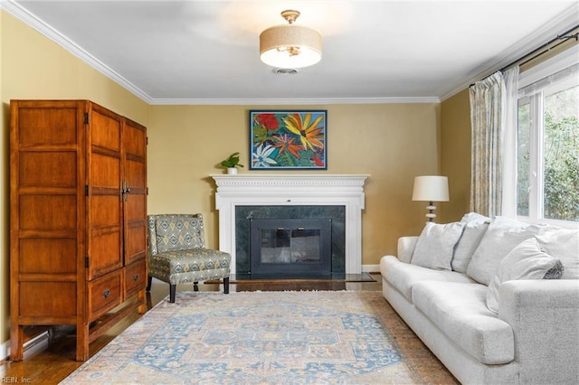 living area featuring a glass covered fireplace, crown molding, and wood finished floors