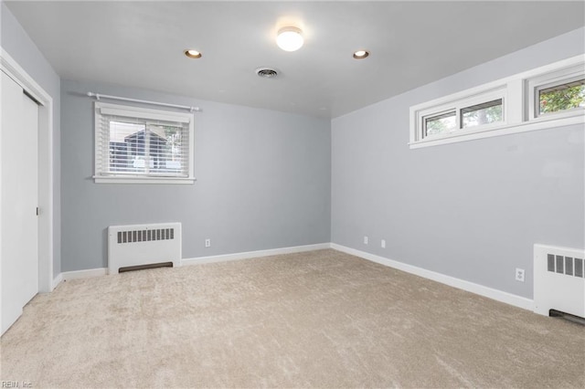 unfurnished bedroom featuring radiator heating unit, carpet, visible vents, and baseboards