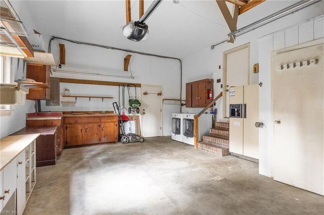 garage featuring a workshop area, white refrigerator with ice dispenser, a garage door opener, and independent washer and dryer