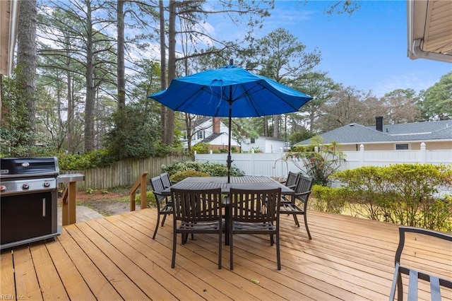 wooden terrace featuring grilling area, outdoor dining area, and a fenced backyard