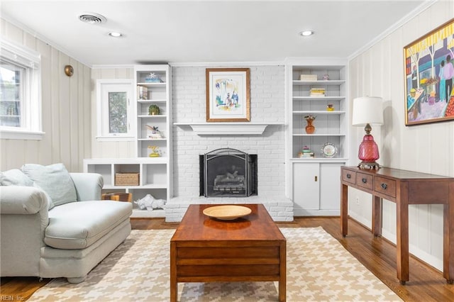 sitting room featuring visible vents, built in features, crown molding, and wood finished floors