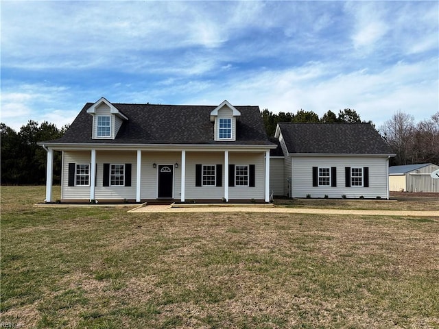 view of front of house featuring a front yard, covered porch, and a shingled roof