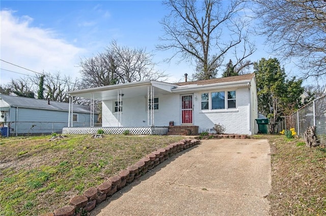 view of front of house with brick siding, covered porch, a front lawn, and fence