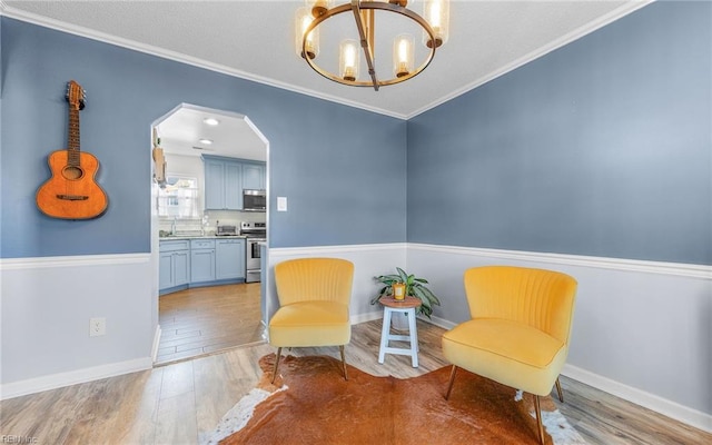 living area featuring baseboards, arched walkways, wood finished floors, and crown molding