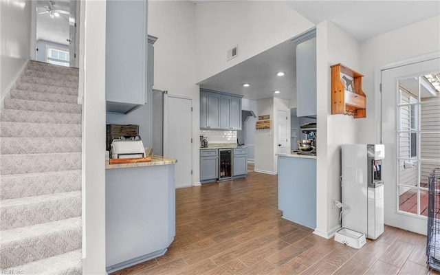 kitchen with gray cabinets, decorative backsplash, dark wood-type flooring, wine cooler, and light countertops