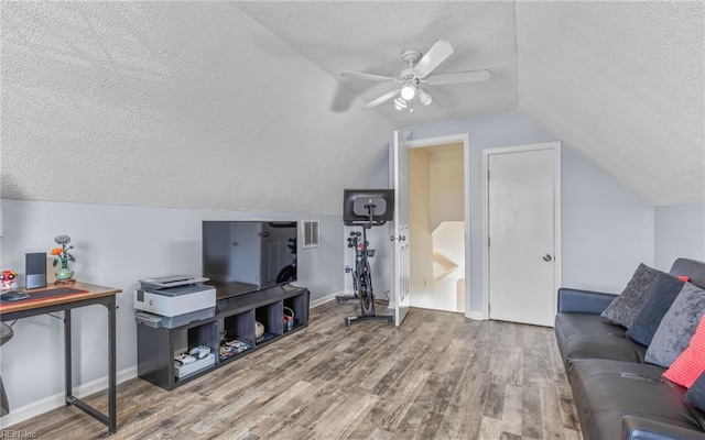 living area featuring a textured ceiling, baseboards, and wood finished floors