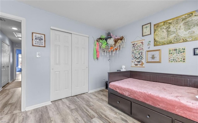 bedroom with a closet, baseboards, and light wood-style floors