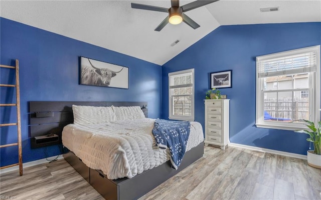 bedroom with visible vents, baseboards, lofted ceiling, and wood finished floors