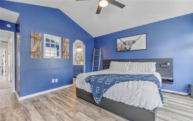 bedroom featuring lofted ceiling, a ceiling fan, wood finished floors, arched walkways, and baseboards