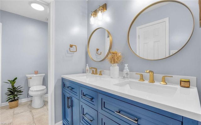 bathroom featuring a sink, baseboards, toilet, and double vanity