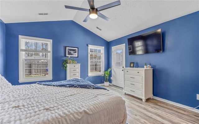 bedroom featuring visible vents, a textured ceiling, light wood-style flooring, and vaulted ceiling