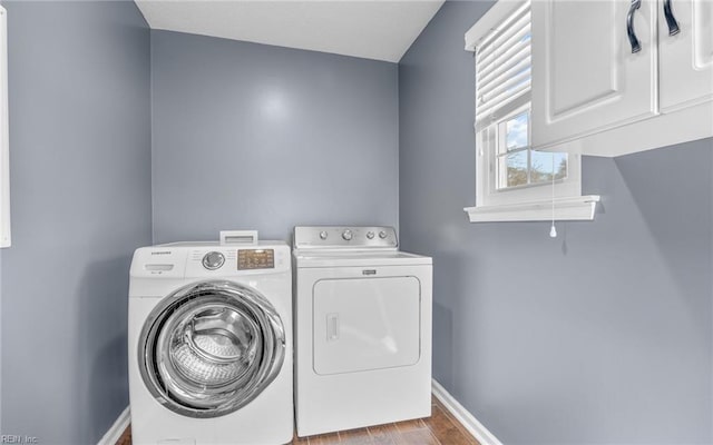 laundry room with baseboards, cabinet space, separate washer and dryer, and wood finished floors