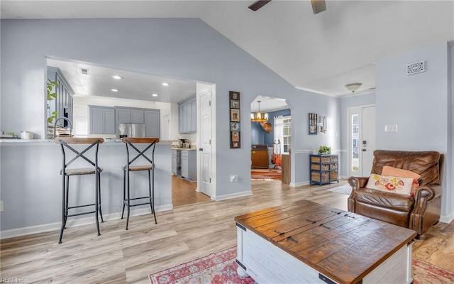 living area with arched walkways, a ceiling fan, lofted ceiling, and light wood-style floors