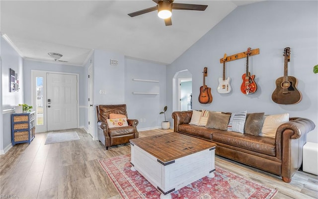 living area featuring arched walkways, crown molding, light wood-type flooring, and vaulted ceiling