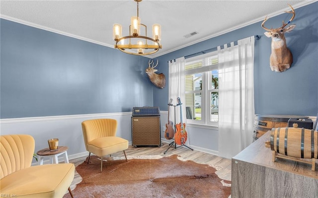 sitting room featuring a chandelier, visible vents, crown molding, and wood finished floors