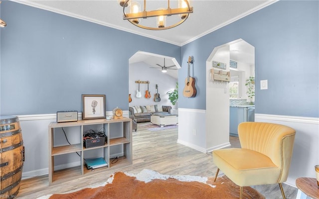 living area featuring wood finished floors, arched walkways, vaulted ceiling, crown molding, and ceiling fan with notable chandelier