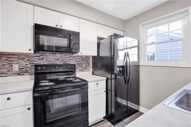 kitchen featuring decorative backsplash, white cabinets, black appliances, and a sink