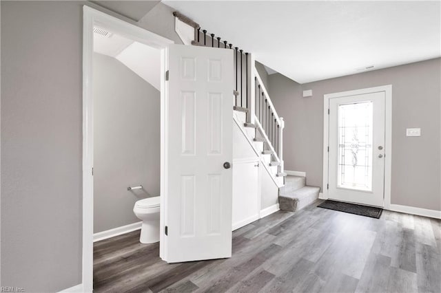 foyer featuring stairway, baseboards, visible vents, and wood finished floors