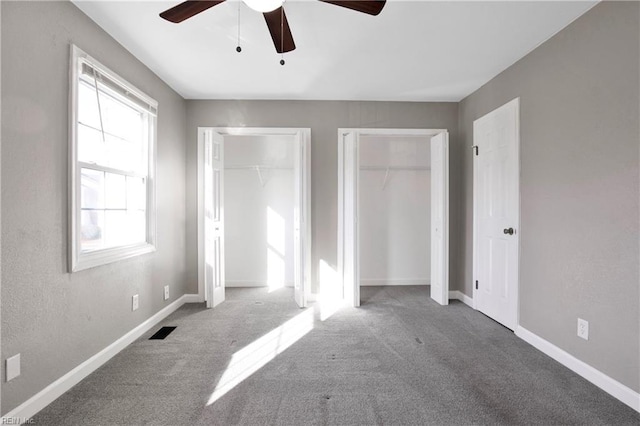 unfurnished bedroom featuring carpet, visible vents, multiple closets, and baseboards