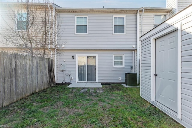 rear view of property with cooling unit, a lawn, and fence