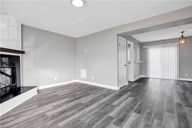 unfurnished living room featuring wood finished floors, baseboards, and a large fireplace