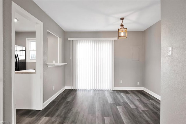 empty room with baseboards, dark wood-style floors, and a textured wall