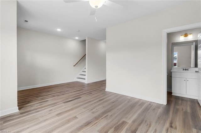 unfurnished room with a ceiling fan, wood finished floors, recessed lighting, baseboards, and stairs