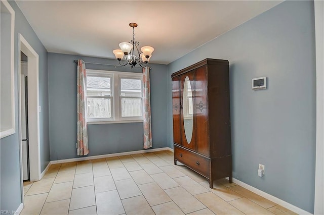 unfurnished room featuring a notable chandelier, baseboards, and light tile patterned floors