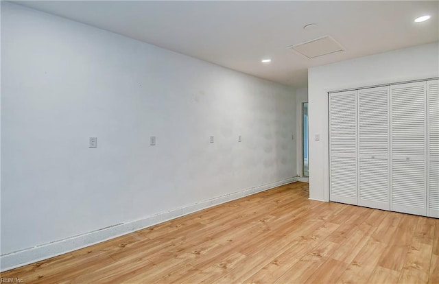 unfurnished bedroom with baseboards, attic access, light wood-style flooring, recessed lighting, and a closet