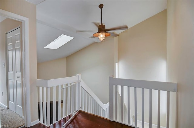 hall featuring lofted ceiling with skylight and an upstairs landing