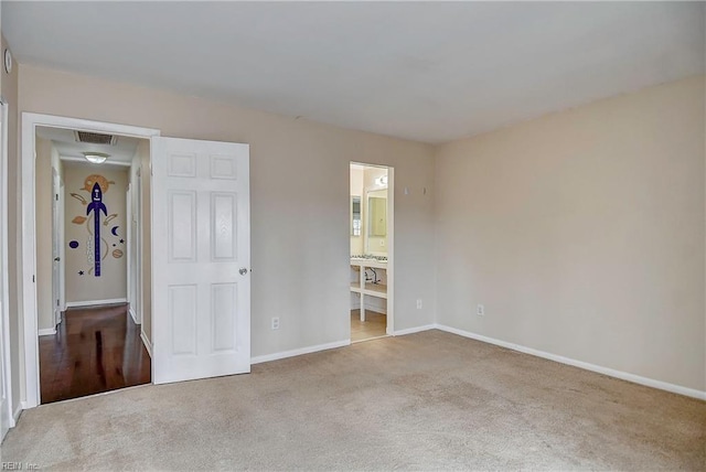 unfurnished bedroom featuring visible vents, baseboards, ensuite bathroom, and carpet flooring