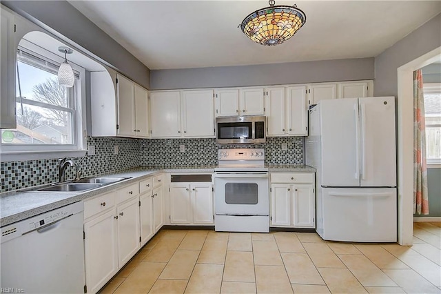 kitchen with a sink, decorative backsplash, white appliances, and white cabinetry