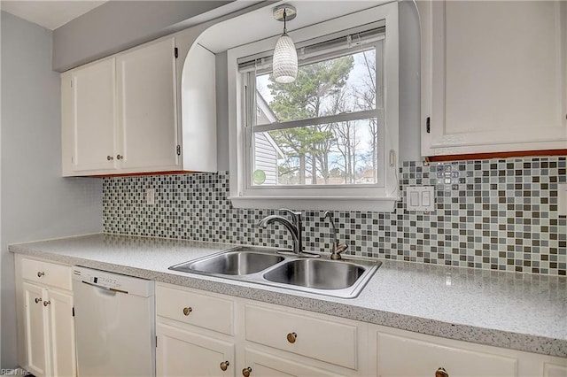 kitchen featuring a sink, backsplash, white cabinetry, white dishwasher, and light countertops