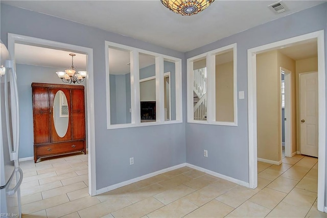 foyer entrance featuring light tile patterned floors, visible vents, baseboards, and a chandelier