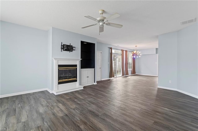 unfurnished living room with a glass covered fireplace, dark wood-type flooring, ceiling fan with notable chandelier, and baseboards