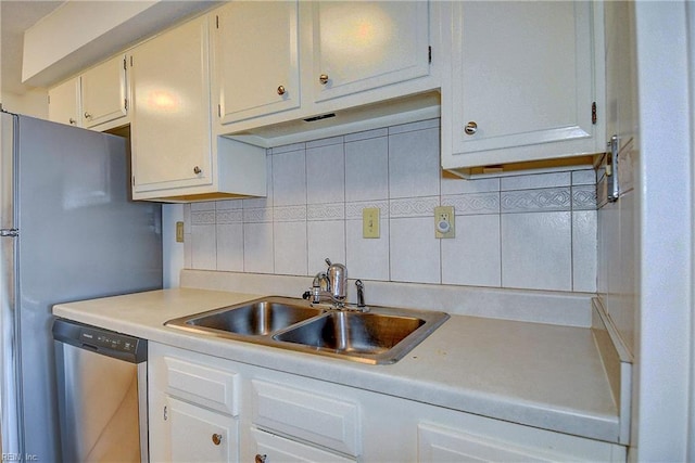 kitchen with tasteful backsplash, light countertops, stainless steel appliances, white cabinetry, and a sink