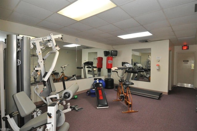 exercise room featuring a paneled ceiling and baseboards