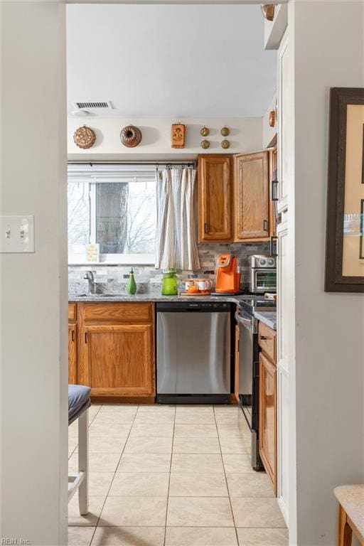 kitchen with brown cabinetry, visible vents, backsplash, and stainless steel dishwasher