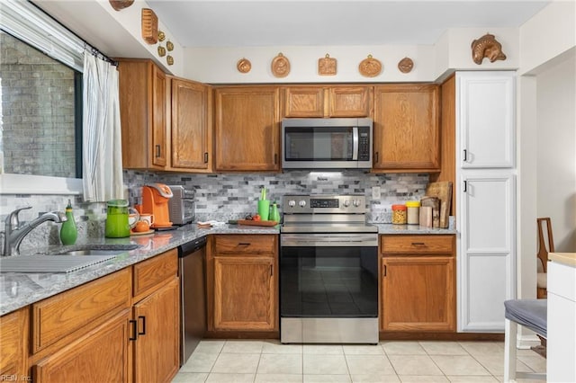 kitchen featuring tasteful backsplash, brown cabinets, appliances with stainless steel finishes, and a sink