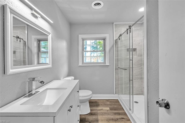 bathroom with vanity, wood finished floors, visible vents, a stall shower, and toilet