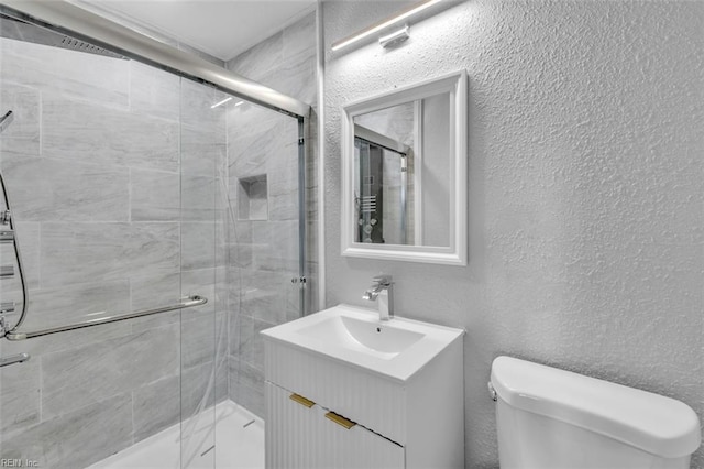 full bathroom featuring a stall shower, toilet, vanity, and a textured wall