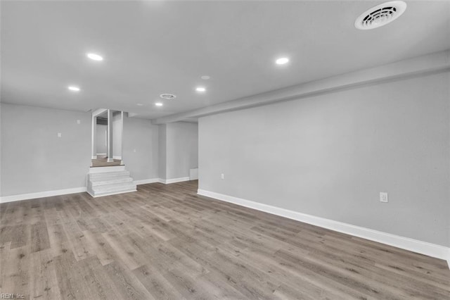 finished basement with wood finished floors, visible vents, baseboards, recessed lighting, and stairs